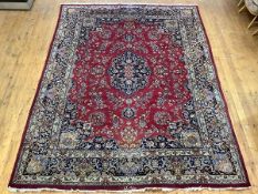 A North-West Persian hand-woven wool carpet, the red field with shaped indigo centre medallion and