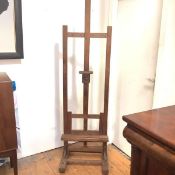 An Edwardian pine artist's easel, of characteristic form, with dual rests, on a trestle base.
