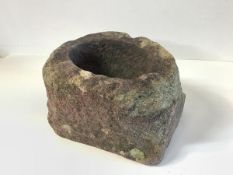A carved stone mortar, roughly-hewn, with hollowed-out well, possibly Bronze Age. 15cm by 21cm by