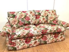 A modern floral upholstered three-seater sofa, with detachable cushion back and seat, between