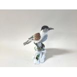 A German porcelain model of a bird, modelled perched on a stump, with blue crossed swords mark
