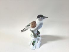 A German porcelain model of a bird, modelled perched on a stump, with blue crossed swords mark