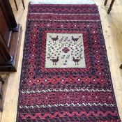 A North West Persian rug, the central panel decorated with stylised birds within indigo and madder