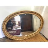 A large oval giltwod wall mirror, the plate within a carved fluted frame incorporating beaded and