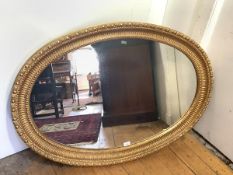 A large oval giltwod wall mirror, the plate within a carved fluted frame incorporating beaded and