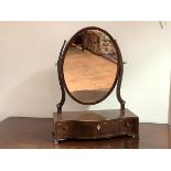 An early 19th century mahogany toilet mirror, the oval plate within scroll supports, on a serpentine