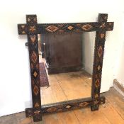 A 19th/early 20th century "Tramp Art" carved wooden mirror, the rectangular plate within a frame