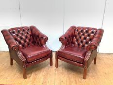 A pair of modern leather club chairs, each with buttoned back and scroll arms, with close-nailed