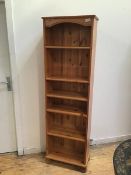 A modern pine open bookcase fitted five adjustable shelves on bun feet (179cm x 55cm x 29cm)