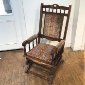 A 1930s/40s rocking chair with stylised flowerhead upholstery to back, seat and arms, with