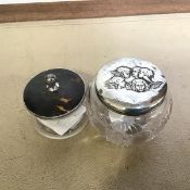 Two silver mounted cut glass dressing table jars, the first Birmingham 1905, lid chased with putti