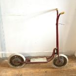 A vintage Tri-ang scooter, painted red, with Tri-ang Toys Ltd stamp to front
