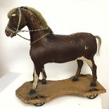 An early 20thc toy horse, with ponyskin body and horsehair mane and tail, on wooden base, with