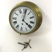 A brass porthole style wall clock, complete with key (glass loose) (10cm x 26cm)