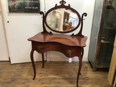 A late 19thc French mahogany dressing table, the oval mirror with carved scroll surmount and