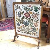 A 1930s firescreen, the embroidered panel with a foliate design, within an oak frame (86cm x 60cm