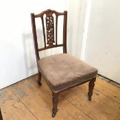 An Edwardian nursing chair pressed with central rosette above a pierced floral splat with