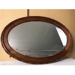 A modern mahogany oval wall mirror with bevelled glass plate and beaded edge (60cm x 86cm)