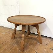 An Arts & Crafts oak occasional table, the circular top with raised edge on four turned supports