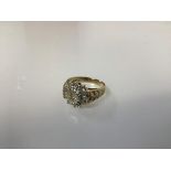 A 9ct gold diamond cluster ring in a flowerhead setting with leaf cast shoulders (O) (4.88g)