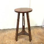 An Arts & Crafts oak stool with circular top on tripod support united by concave undertier (69cm x