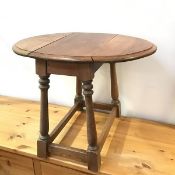 An early 20thc oak drop leaf occasional table, the oval top on four splay turned supports united