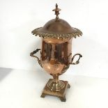 A copper lidded urn with foliate rim, handles to side, on footed square base, lacking wooden