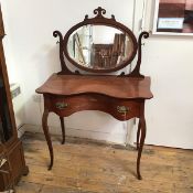 A late 19thc French mahogany dressing table, the oval mirror with carved scroll surmount and