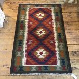 A kelim rug with triple diamond shaped medallions enclosed within a stylised motif border (132cm x