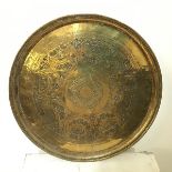 A Middle Eastern brass tray with raised edge above a decorated well (d.49cm)