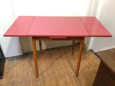 A 1960s extending kitchen table with coral coloured formica top on beech frame (extended: 77cm x