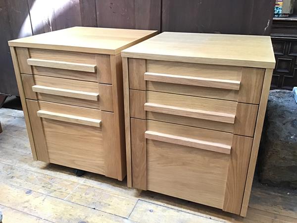 A pair of modern oak office cabinets fitted two drawers, larger fitted for hanging files, on castors