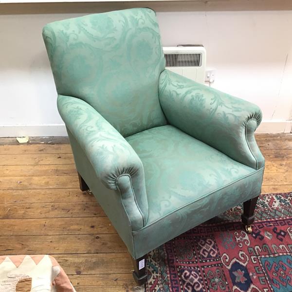 A 1920s/30s upholstered armchair with a flower and leaf pattern, on tapering supports terminating in