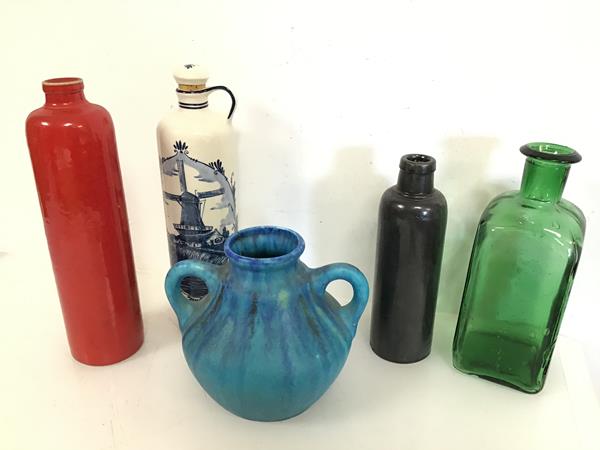 A stoneware bottle with red glaze and another with black/grey glaze, a green square cased bottle,