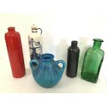 A stoneware bottle with red glaze and another with black/grey glaze, a green square cased bottle,
