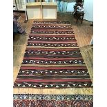 A large kelim flatwoven rug with multiple rows of geometric patterns with bands of soft brown and