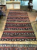 A large kelim flatwoven rug with multiple rows of geometric patterns with bands of soft brown and