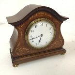 An Edwardian mahogany mantel clock with domed top above an inlaid body and brass bun feet, the