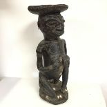 A carved African wooden stool in the form of a Woman Kneeling, possibly in a Fertility Pose, with