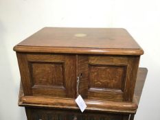 A 1930s oak cutlery canteen with two panel doors enclosing three fitted drawers, complete with a set