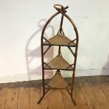 A 1920s/30s bamboo and wicker etagere with ring finial and three tiers, on splay feet (89cm x 27cm x