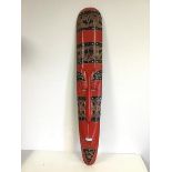 A Tribal mask of long slender form, painted red with further decoration (98cm x 18cm)