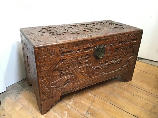 A Chinese camphorwood chest, carved with typical Chinese scenes to all sides, unfitted interior,