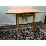 A 1960s/70s beech formica top kitchen table with fold up sides, fitted single frieze drawer, on