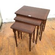 A reproduction set of mahogany nesting tables, the crossbanded top above a reeded edge, on turned