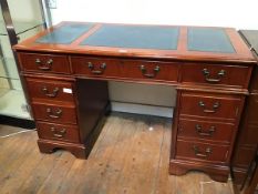A reproduction cherrywood pedestal desk with tooled leather top, fitted one long and two short
