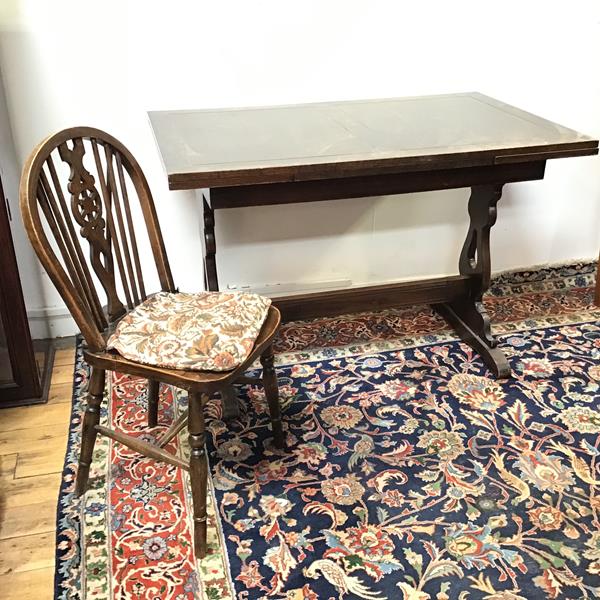 A 1920s oak draw leaf trestle dining table and a set of Windsor wheel back dining chairs (table