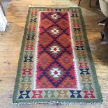 A kelim rug, the centre panel with four diamond medallions enclosed within a stylised column border,