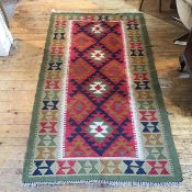 A kelim rug, the centre panel with four diamond medallions enclosed within a stylised column border,