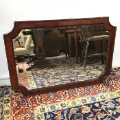An Edwardian mahogany mirror, the bevelled glass within a mahogany frame, with concave corner and